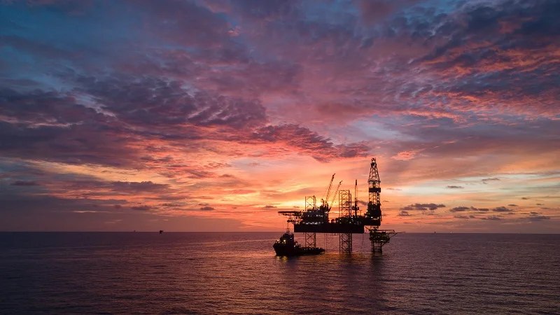 An offshore oil platform at sunset.