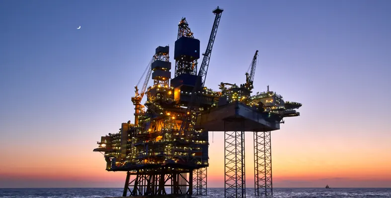 An offshore oil and gas platform at sunset.