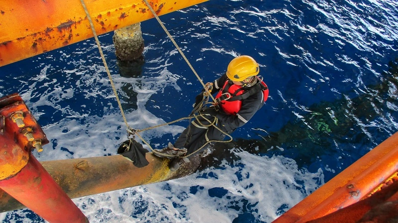 Image of a man inspecting an offshore pipe. 