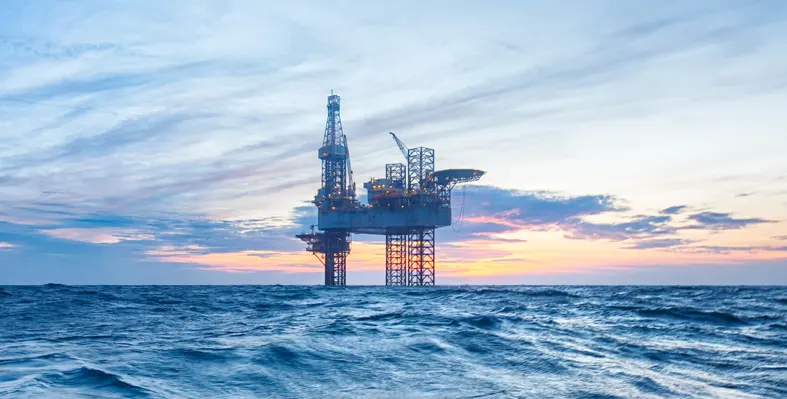 An offshore oil and gas platform at sunset.