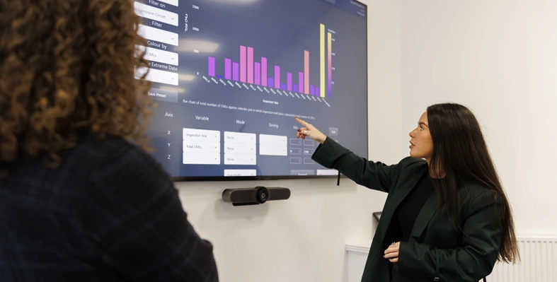 A woman looking at statistics on a big screen 