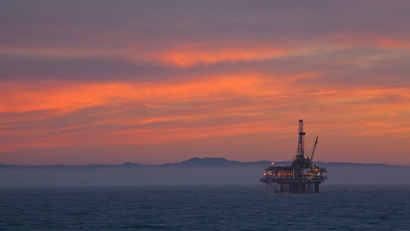 Image of an oil platform against a sunset backdrop