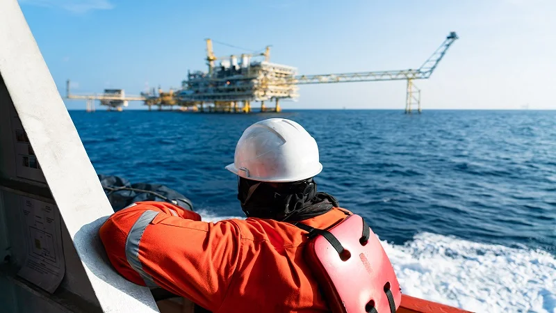 An offshore oil worker looking at a platform in the distance