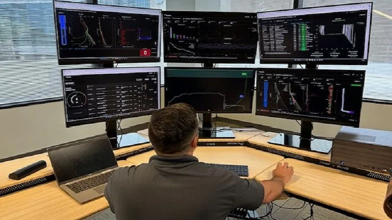 An engineer monitoring pipe systems on six screens.