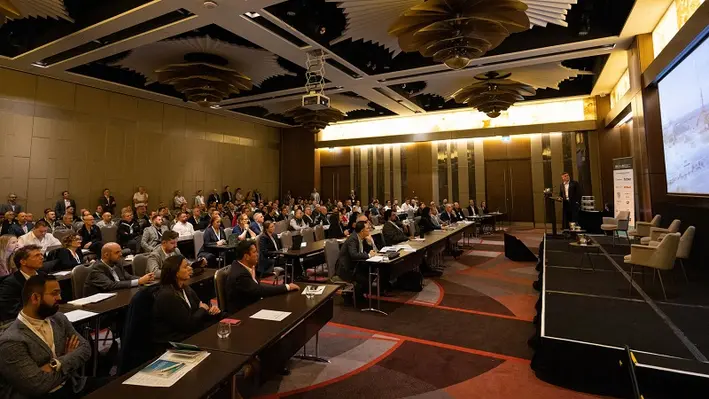 Image of a full room at a conference listing to the speak on stage 