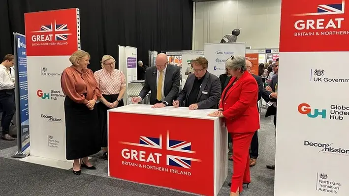 Neil Gordon of Global Underwater Hub (centre left) and Colin McIvor, Subsea Innovation Cluster Australia, signing the memorandum of understanding on Global Underwater Hub's stand at EXA in Perth, Australia