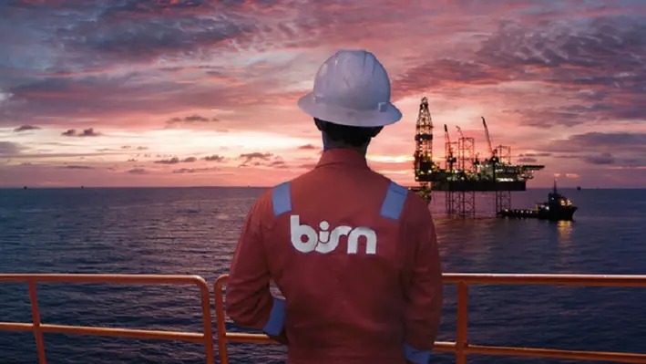 A BiSN sunset image crewmember in foreground rig in distance
